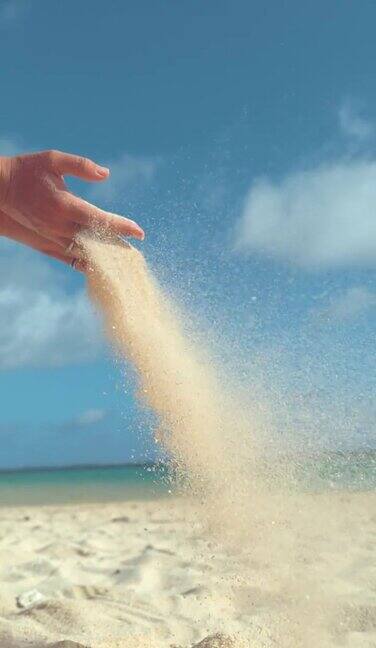 垂直慢动作:小沙粒从女性手中被吹走