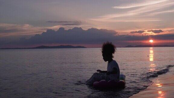 女孩坐在海边落日的剪影