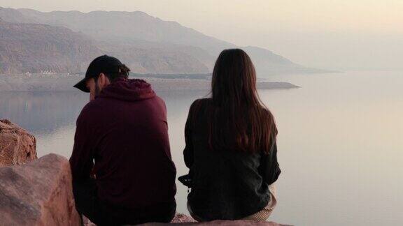 约旦死海上的一对年轻夫妇凝视着落日美景