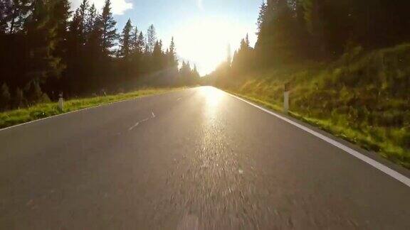 在蜿蜒的道路上行驶穿过森林阳光透过树木