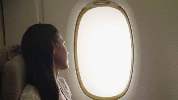 一个女人在飞机上放松去度假在她舒适的座位上从窗口你可以看到天空的云