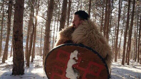 中世纪武士的后视镜在冬天带着长矛和盾牌在森林里行走