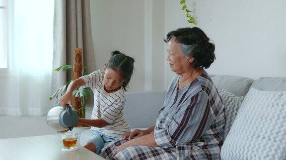 孙女正在把茶倒进杯子里给客厅里的奶奶倒了一杯茶