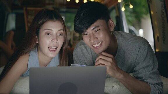 亚洲情侣在露营车上用电脑网购的场景