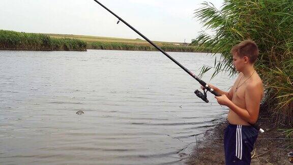 一个少年拿着钓竿在湖边钓鱼