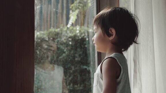一个亚洲小男孩站在窗边