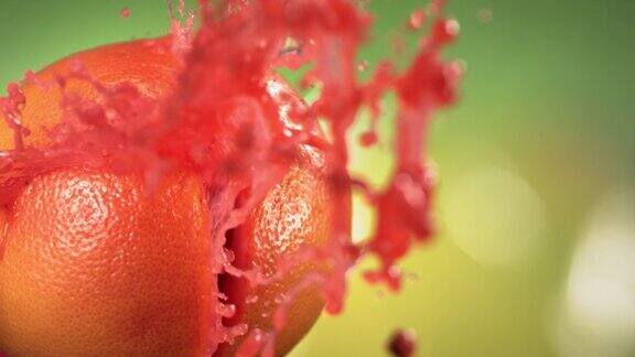 新鲜柚子喷射果汁在绿色自然背景的慢动作4K