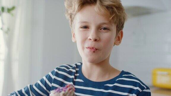 在厨房里:可爱的男孩吃着奶油蛋糕上面有糖霜和撒上Funfetti可爱饥饿的甜牙孩子咬松饼与含糖糖霜