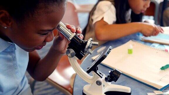 可爱的非裔美国STEM学校学生用显微镜检查东西