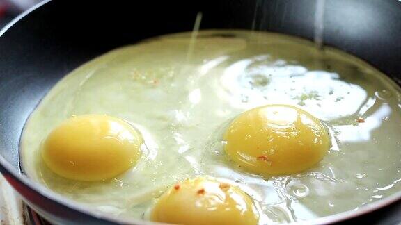 早餐刚炒好的鸡蛋在煎锅里撒上香料