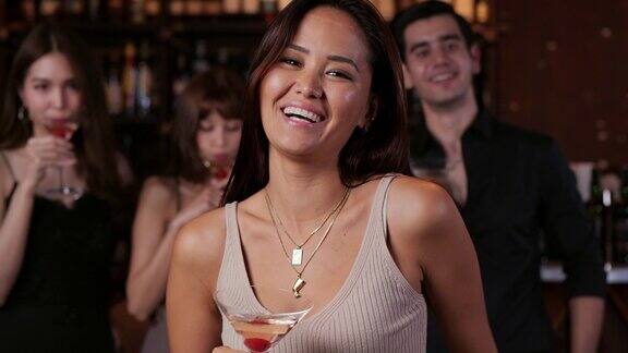 肖像亚洲美丽的女人拿着葡萄酒或鸡尾酒饮料与迷人的微笑她站在餐厅酒吧看着镜头