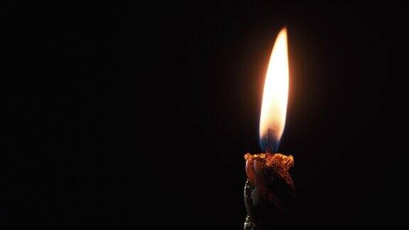 在黑色背景上点燃一支蜡烛黑暗中的蜡烛火焰