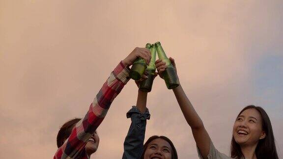 年轻的亚洲女人快乐的朋友露营在自然有乐趣一起喝啤酒和碰杯和朋友一起喝啤酒看日落