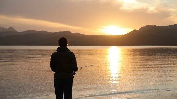 日落下正在湖边钓鱼的女孩