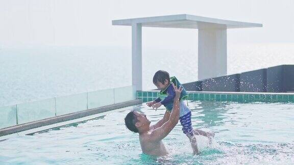 年轻的亚洲父亲和他的儿子在游泳池里玩