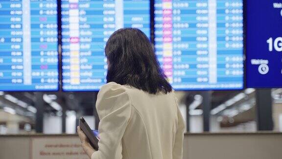 年轻的亚洲商务女性在国际机场候机楼门口检查商务旅行计划和航班时间表确认与同事的会议文件