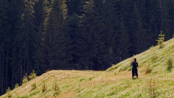 穿着黑色长外套的女人独自走在山中