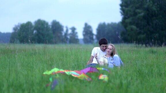 一对相爱的年轻情侣躺在草地上拥抱着交谈着
