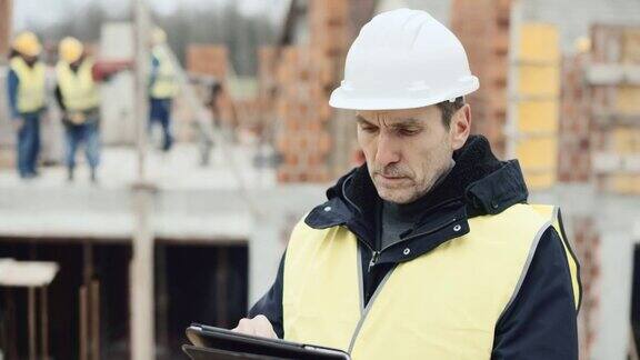 男建筑师站在建筑工地检查数字平板电脑上的平面图