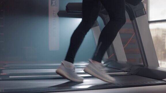 近距离观看男人的腿在跑步机上跑步在健身房慢动作
