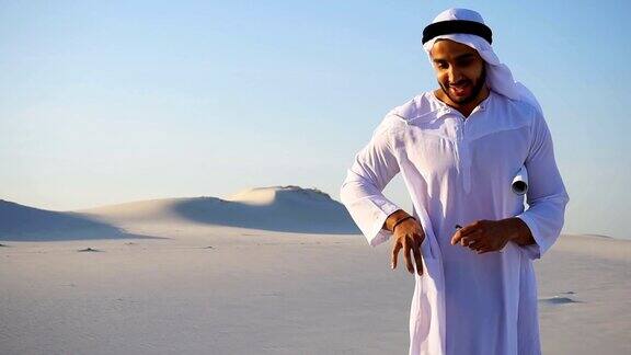 男阿联酋设计师阿拉伯谢赫站在白色的沙漠中对着天空完成建筑工地的勘察并接听客户的电话