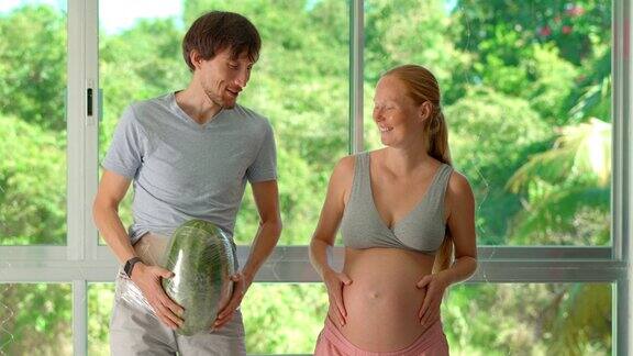 在这个幽默的慢镜头视频中一位孕妇开玩笑地把一个西瓜拴在她男人的肚子上创造了一个轻松的模拟怀孕的体重和体验他们一起跳舞玩得很开心这段视频庆祝了t的快乐