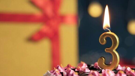 生日蛋糕3号金色蜡烛用打火机点燃蓝色背景的礼物黄色盒子用红丝带扎起来特写和慢动作
