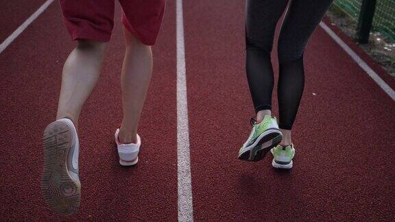 慢动作的年轻人穿着运动鞋在体育场上跑步