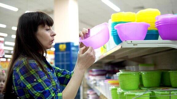 一位年轻的妇女在超市挑选并购买了一个塑料碗