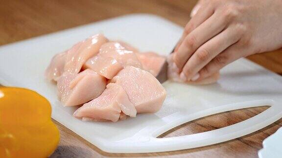 女厨师在切菜板上切生鸡肉