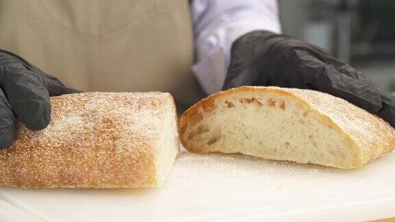 专业厨师将新鲜出炉的意大利脆皮面包切成两部分展示面包的品质孤立木质表面意大利食品