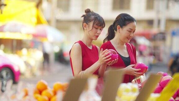4K亚洲母亲和女儿在唐人街购买庆祝中国农历新年的新鲜水果