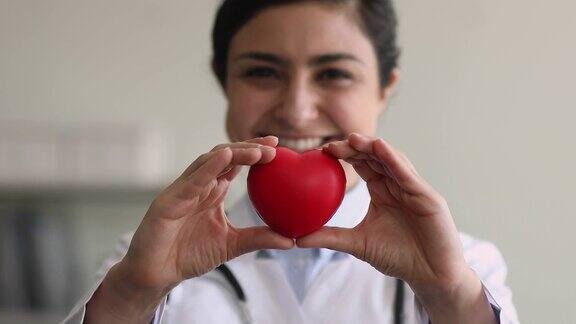 特写印度心脏病专家女性向相机展示红心