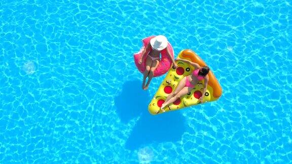 空中女友享受充气披萨和甜甜圈漂浮在游泳池里的乐趣