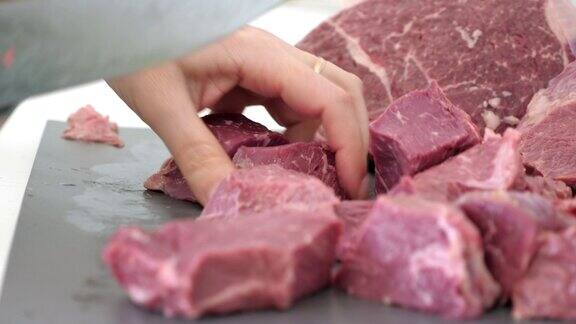 妇女切生牛肉块烧烤为烧烤准备肉类