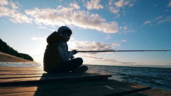 一个男孩在阳光下的码头上钓鱼