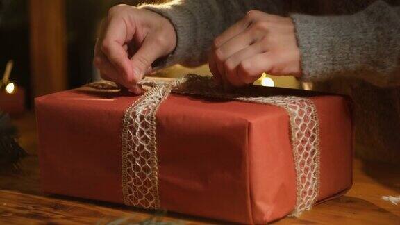 女性用手在圣诞礼物盒上系蝴蝶结