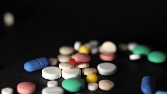 药店的主题黑色桌子上的彩色药片和胶囊维生素落在深色的表面慢动作