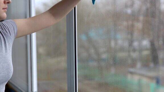 年轻女子用一块蓝抹布擦窗户