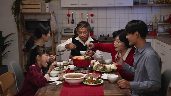 亚洲大家庭聚在一起吃团圆饭喝土司吃火锅在一个舒适的室内庆祝农历新年