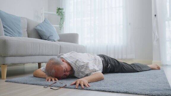 亚洲老年男性在家中独自行走时摔倒在地成熟的老爷爷退休后在家里的客厅做物理治疗意外晕倒