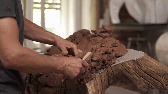 在专业的艺术工作室里男性雕塑家的手拿和塑造陶土创作陶瓷雕塑的特写
