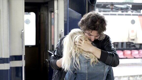 下雨天在火车站的站台上一对相爱的美丽情侣告别亲吻