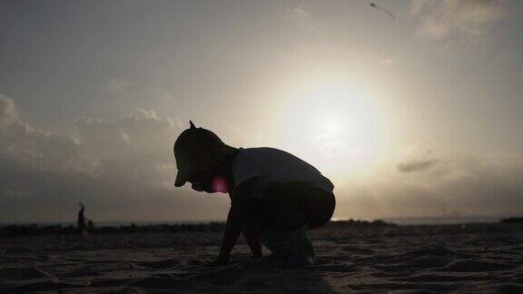 日落时分小男孩在海滩上玩耍慢动作