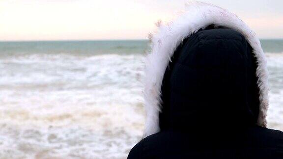 女人在冬季夹克与兜帽看大海日出前特写