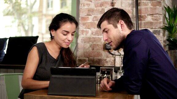 浪漫的年轻夫妇使用平板电脑用信用卡支付坐在咖啡店的平板电脑网上购物智能、快捷、方便