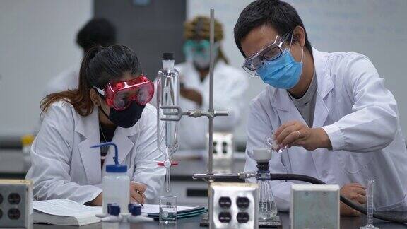 多民族学生戴着口罩在实验室工作