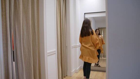 一位年轻女子在一家服装店的试衣间里试穿一件黄色的便服