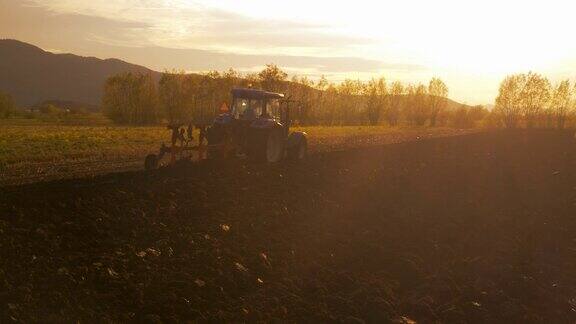 美丽的夕阳下农夫在拖拉机上工作