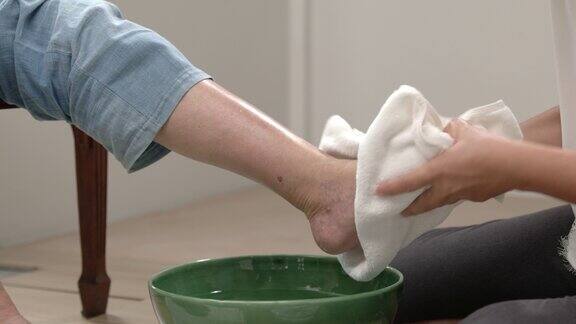 女性护理人员用生理盐水按摩和清洁老年妇女的脚